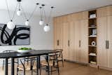 The dining area cabinetry features the same wood as the kitchen, designed to balance open shelving with closed storage.