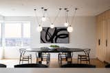 The dining area is designed to feel minimal and airy, while the DCW Éditions Les Acrobates chandelier anchors the space with a striking sculptural presence.
