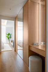 The hallway leading to the primary bedroom is lined with wood cabinetry that seamlessly integrates a makeup station, storage, and built-in mirrors.