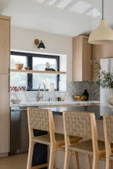 Kitchen, Pendant Lighting, Stone Counter, Wall Lighting, Stone Slab Backsplashe, Undermount Sink, Wood Cabinet, and Light Hardwood Floor  Photo 5 of 15 in Ocean Views For Days by Katie Betyar