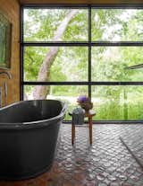 The serene principal bathroom features floor-to-ceiling windows and a deep soaking tub where the artist unwinds every evening.