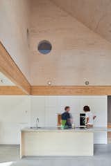 The open, double-height kitchen features two round peepholes that create&nbsp;a visual connection between the cooking area and the upper floor.