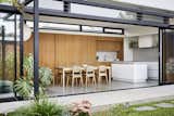 An extension for a family of four in Melbourne placed the kitchen in a newly constructed garden terrace, maximizing connection to the outdoors. An impressive 30-foot glazed opening spans the length of the extension, allowing a seamless flow between the kitchen and greenery.