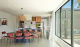 Light floods into the home's open kitchen, dining, and living rooms through striking large glass windows facing the inner courtyard.