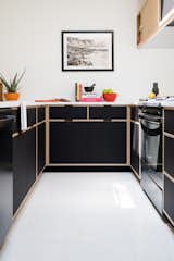 Kitchen, Terrazzo Floor, Wood Cabinet, Range, and Laminate Cabinet The cabinets in this u-shaped kitchen are exposed edge plywood with a mix of rift-sawn oak veneer and Wilsonart Black Velvet laminate. Photo by Sarah Shields  Photo 5 of 7 in Bloomington Flansburgh House by Susan Yeley