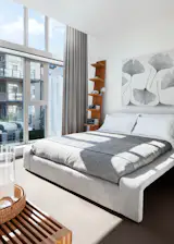 a restful bedroom with linen drapes and a leaning bookshelf to emphasise the high ceilngs