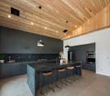 Charcoal inspired custom kitchen with soaring 15' vaulted ceilings, waterfall center island, black subway tiles and concrete flooring