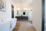 Master bath oasis featuring an oversized walk-in shower, white subway tile, soaking tub and floating black cabinetry with dual sinks