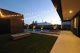 Outdoor living with rectangular modern fireplace bit, covered patio opening to a sun deck, swimming pool and pool house