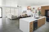 Open floorplan with gathering room off the kitchen that showcases custom Walnut cabinetry and white quartz waterfall center island