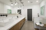 The Master Bath experience showcasing a white modern vanity with dual sinks, black Brizo fixtures and curb-less IPE shower floors 