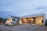 Modern exterior architecture featuring a store-front commercial front door, metal roof, white stucco and wood paneling