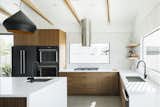 Modern kitchen with black hardware, pendant lighting, stainless appliances, white quartz countertops and Walnut cabinets