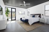 Master Bedroom with black aggregate cement floor, painted black ceiling detail and commercial steel door with access to the patio area
