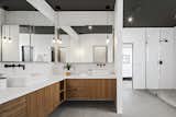 A modern Master Bath sanctuary featuring walnut cabinetry, cement flooring, dual sinks, white quartz countertops and unique lighting fixtures