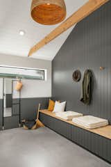 Drop zone / mudroom with custom built-in bench area, black shiplap details that go floor-to-ceiling, exposed wood beams and white shiplap ceiling.