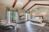 This master suite measures 23' x 14' and has 13' vaulted ceilings with wood beams and Restoration Hardware ceiling fan and chandelier, as well as dual French doors with Ashley Norton hardware that lead to the 37 1/2' wide balcony.
