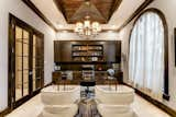 Wood stain accents provide warmth while a wood stained groin vault ceiling and French doors provide formality to this handsome study. Coupled with  custom built-in cabinetry and massive, arched windows, this home office is a perfect place to work efficiently. 