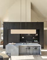 This monolithic kitchen wall is crafted from wood charred black in the Japanese shou sugi ban method and neatly conceals abundant storage. Large sculptural kitchen islands are crafted from Caesarstone-quartz, a nod to bluestone from the Catskill Mountain region.