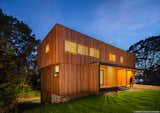 Interior lighting animates the facade at night, revealing the entry and windows above