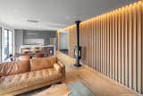 A white oak slat wall illuminated with voice activated lighting creates an abstract curtain to walk through upon entering the home