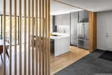 Kitchen, Engineered Quartz Counter, Laminate Cabinet, Recessed Lighting, Light Hardwood Floor, Stone Slab Backsplashe, Refrigerator, and Cooktops The wood slat wall obscures the view upon entry  Photo 9 of 14 in Westport River Retreat by Mark Lawton