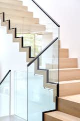 Glass rails are nestled within sleek black steel channels, which features similar black steel channels as handrails, avoiding the heavy, ubiquitous steel buttons seen in most contemporary homes, and maintaining the effortless design. 