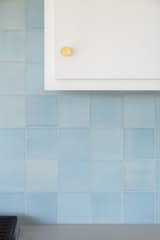 Blue ceramic kitchen tile with white cabinets and bushed gold finished hardware.