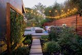 Outdoor, Back Yard, Garden, Horizontal Fences, Wall, Pavers Patio, Porch, Deck, Gardens, Flowers, Small Pools, Tubs, Shower, Small Patio, Porch, Deck, Hanging Lighting, Hardscapes, Walkways, Decking Patio, Porch, Deck, Post Lighting, Landscape Lighting, Trees, Shrubs, Wire Fences, Wall, and Wood Fences, Wall Bluestone step stones lead the way to the new entertaining space.  Photo 2 of 8 in Modern Suburban Backyard by Secret Garden Landscapes