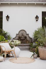 A lush courtyard with a stone fountain and gas lanterns.