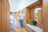 Past the front door, a screen of white oak divides the foyer from the great room. The storage wall on the right includes a bench and drawers for storing shoes, a wet bar , and a closet hiding the washer and dryer on the far end. The large round mirror is from Crate & Barrel. 