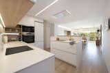 Kitchen, Ceiling Lighting, Medium Hardwood Floor, Wall Oven, Track Lighting, Refrigerator, Cooktops, Range Hood, Engineered Quartz Counter, Wood Cabinet, Undermount Sink, Pendant Lighting, Dishwasher, and White Cabinet  Photo 13 of 20 in A homely and modern flat with Nordic charm by Sincro