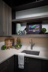 The laundry room features two toned cabinet finishes with a three dimensional panel backsplash and quartz countertops.
