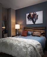The guest suite features a wood and steel headboard against a soft metallic blue wallpaper with a leather grain. The snowy buffalo art and layered textures creates the feeling of the perfect mountain retreat for guests.