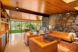 Another view of the living area shows the fireplace wall, clad in locally sourced lava stone. Windows along the rear overlook the lawn and views of Long Lake.