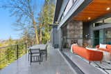 Outdoor, Trees, Metal Fences, Wall, Wire Fences, Wall, Woodland, Concrete Patio, Porch, Deck, and Back Yard Back deck, looking NE, plus Four Seasons Room  Photo 6 of 29 in The Bernstein's Bellingham Bay House by Sylvia Bernstein
