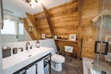 A fully renovated bathroom with a sunken jacuzzi tub optimizes awkward A-frame roofline issues.  Vanity was also custom designed by the owner and fabricated by a local metalsmith.