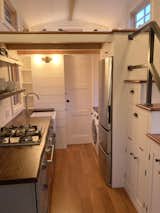 The kitchen features a 4 burner gas cook top, electric oven, farmhouse sink, open shelving, Kraftmaid cabinets, apartment size fridge/freezer, washer and dryer and lots of storage under the staircase/