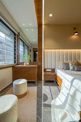 The master bedroom exudes its own style and young personality. The wall paneling behind the bed is reflected from the ceiling. This backdrop from the ceiling to the wall gives a minimalistic ambiance. Back-painted white glass with wooden touch in wardrobe and TV unit reflects the overall charisma of the room.