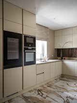 The kitchen has a striking stone veneer backsplash that matches well with neutral countertops and active floor tiles.
