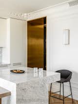 The neutral white walls in the kitchen contrast with the brass portal. 