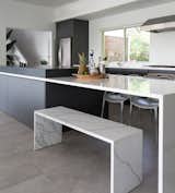 Clean lines define this sleek kitchen featuring marble look counters and coordinating bench