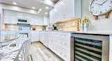 Kitchen, Stone Tile Backsplashe, Refrigerator, Light Hardwood Floor, Dishwasher, White Cabinet, Wine Cooler, Ceiling Lighting, Microwave, Cooktops, and Granite Counter  Photo 6 of 28 in Pipers Run 2 by Jeff Paglialonga