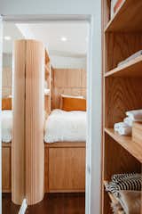 The white-oak ribbon continues into the walk-in closet, which accommodates hanging racks, drawers, and open shelving, in addition to a compact washer and dryer. 