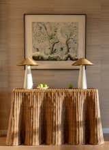Rattan console with plaster lamps, grass cloth wallcovering & the client's artwork