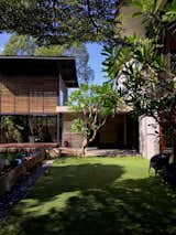 Outdoor, Garden, Wood Patio, Porch, Deck, Large Pools, Tubs, Shower, Trees, Decking Patio, Porch, Deck, and Grass The central lawn connecting the elongated pool to the living area.  Photo 2 of 7 in Denai House by Zakiah Zakariah