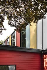 Smoldering Red by Benjamin Moore is painted on the home's exterior horizontal siding. Above, panels in a range of energizing shades, including Wasabi, Fort Pierce, Sunflower Fields, and Bewitched (all by Benjamin Moore) add personality.