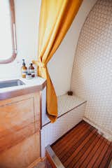 The rose gold trim continues into the bathroom as a decorative accent. A rich orange shower curtain matches the linen sheets and pillows.