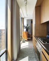 Custom walnut cabinetry conceals appliances from view in the couple's galley kitchen. Stainless steel countertops are welded in with the sink, and sleek Waterworks tile add interest.  Photo 8 of 19 in This Chicago Architect’s Vision for a Buzzy Live/Work Space Started With a Café