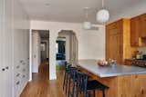 The kitchen walls are painted a crisp white. Doorways with original detailing lead to the adjoining garden-level dining space.